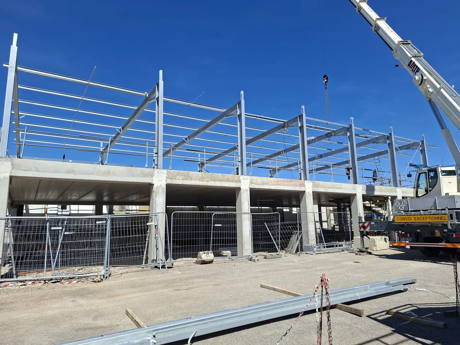 Montage de charpente métallique avec grue sur un bâtiment en construction